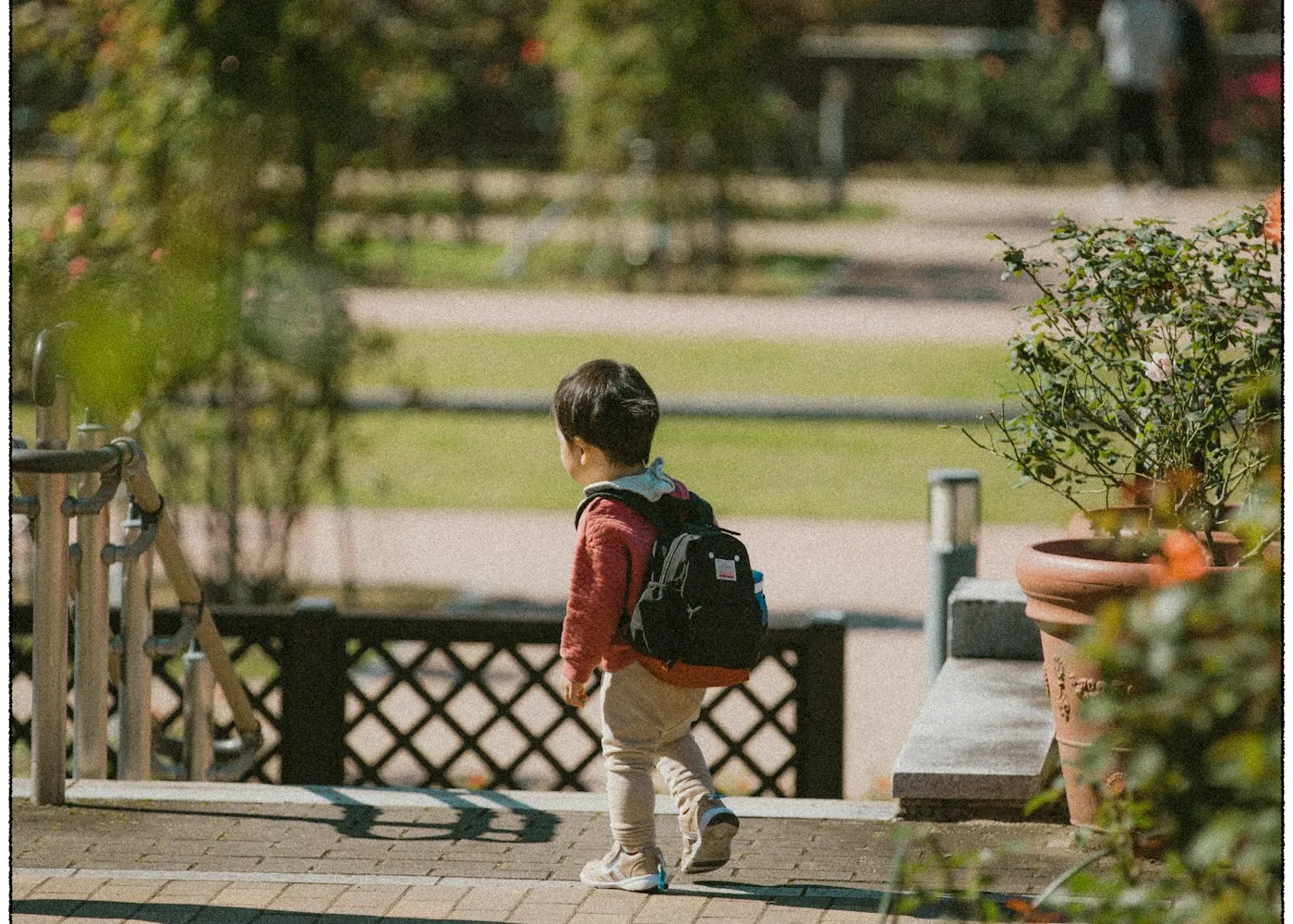 ילד עם תיק גב הולך על שביל בגן ציבורי